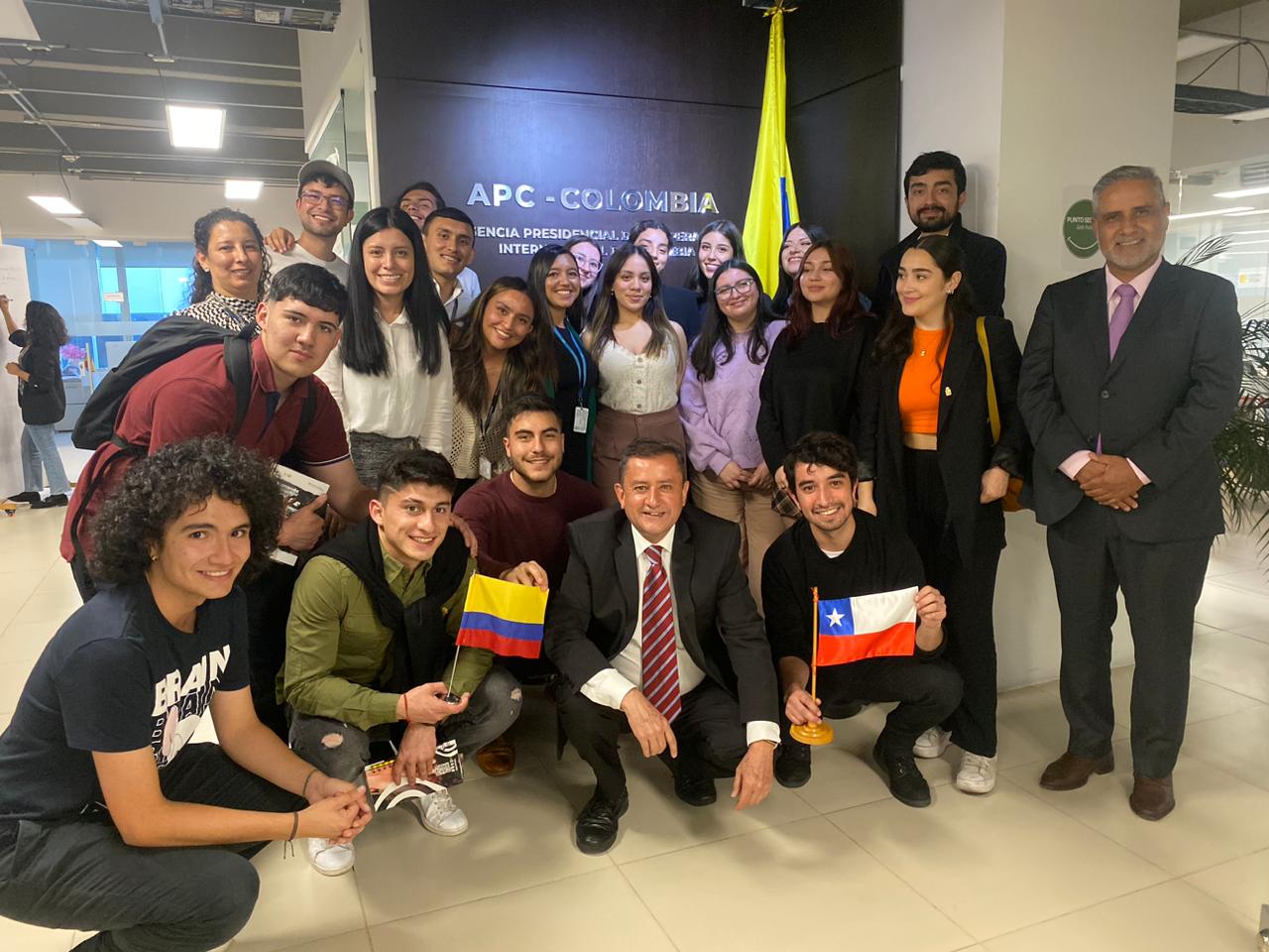 En este modelo se encuentra una delegación de 15 estudiantes de la Universidad de Chile, acompañados por su profesor, quienes visitaron APC Colombia y se realizó un Modelo APC Colombia para que conocieran más de la cooperación en el país. En la foto dos estudiantes de la Universidad de Chile sostienen en su mano la bandera de Chile y Colombia. Para el Modelo, participaron 6 facilitadores