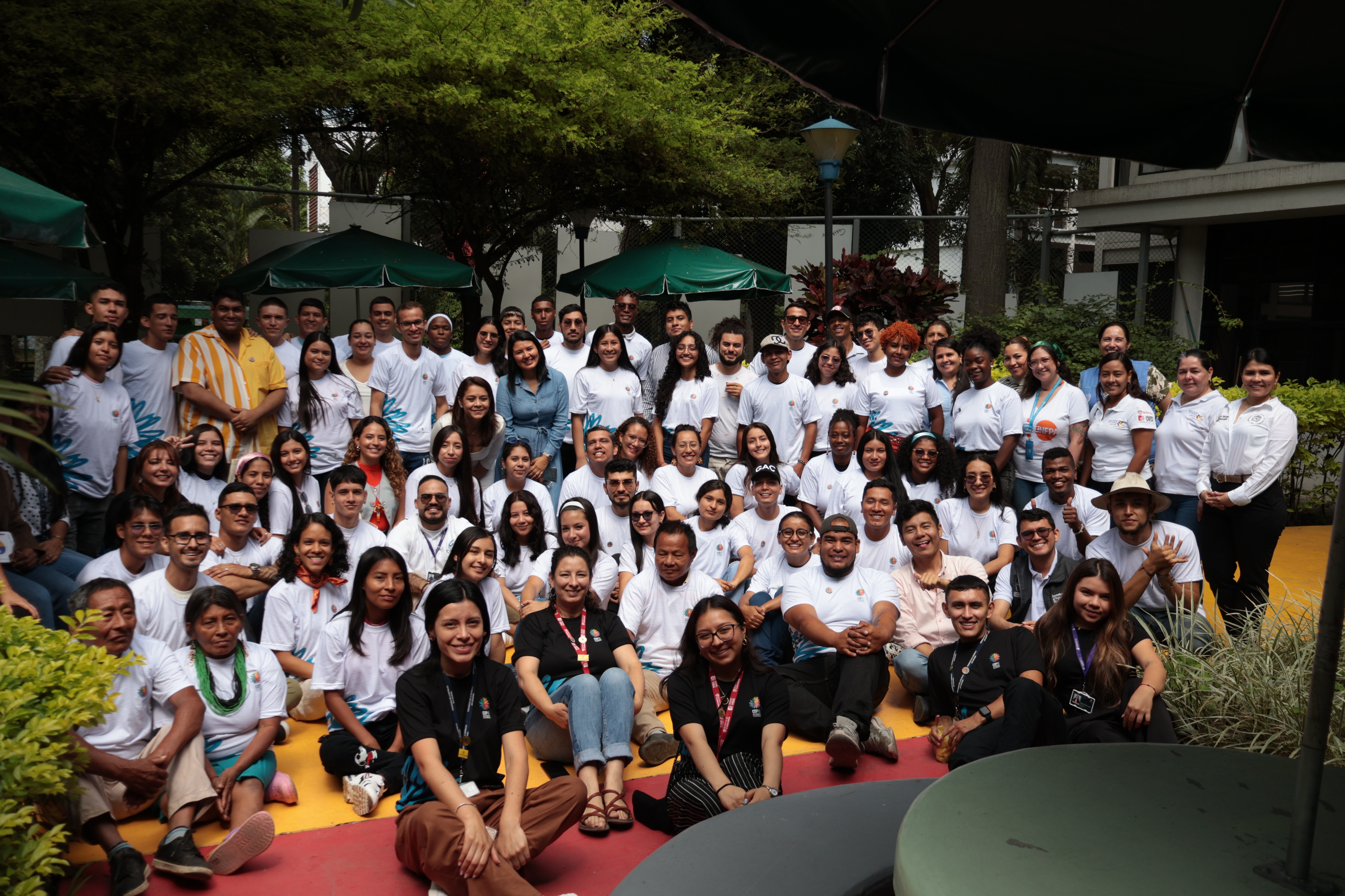 En la imagen se ve a todo el equipo del Observatorio junto a todos los participantes que asistieron a esta sesión del Modelo APC Colombia en la Universidad Nacional de Colombia sede Palmira. En la imagen salen todos los participantes sentados con camisetas blancas con el logo del Modelo APC Colombia en la COP 16