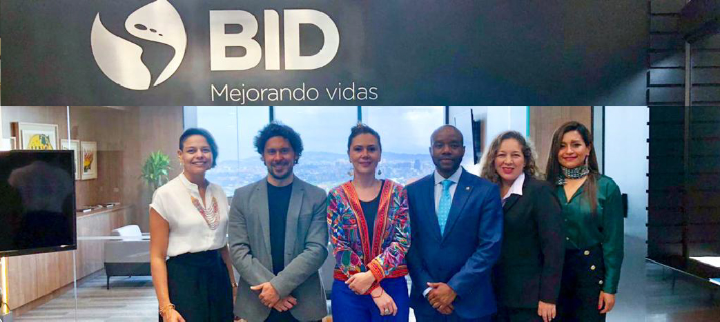 La directora general de APC-Colombia, Eleonora Betancur González con su equipo y el representante del Banco Interamericano de Desarrollo – BID en Colombia, Kelvin Suero con su equipo arriba el logo del BID 