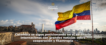 Bandera de Colombia oleándose en el casco antiguo de Cartagena. En la parte superior de la imagen está el escudo del gobierno de Colombia y en la parte inferior el título de la noticia.