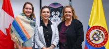 A la derecha la bandera de Colombia, a la izquierda la bandera de Canada, en el medio la directora general de APC-Colombia y la embajadora de Canada