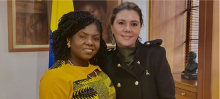 La directora Eleonora Betancur González a la derecha, a la izquierda la vicepresidenta Francia Marques, detrás de ellas la bandera de Colombia